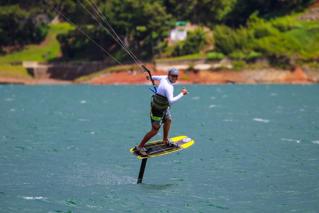 Kite foiler riding a hydrofoil above the water with a shaka sign
