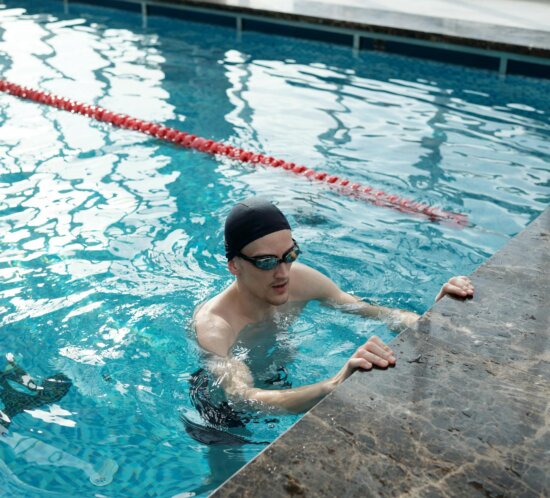 Schwimmer mit Badekappe und Brille trainiert im Hallenbad