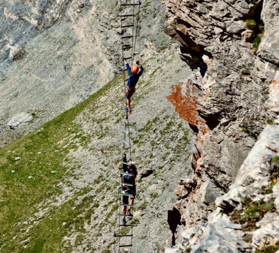 Kletterer auf einer Via Ferrata Leiter an einer steilen Felswand in den Alpen