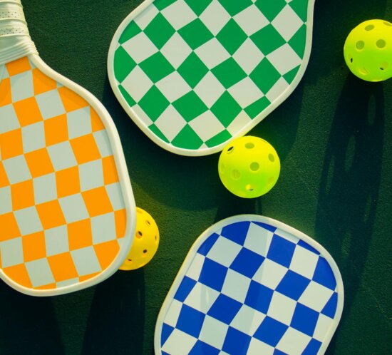 Bunte Pickleball-Schläger und Bälle auf einem sonnigen Sportplatz