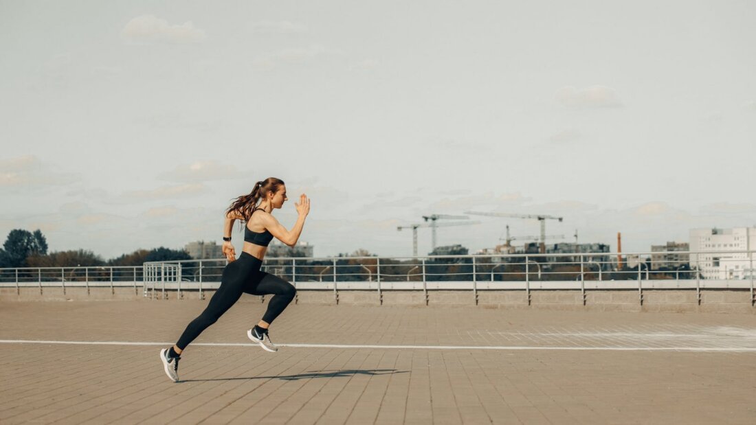 Sportlerin springt athletisch auf Rooftop, Action-Shot ohne erkennbares Wearable