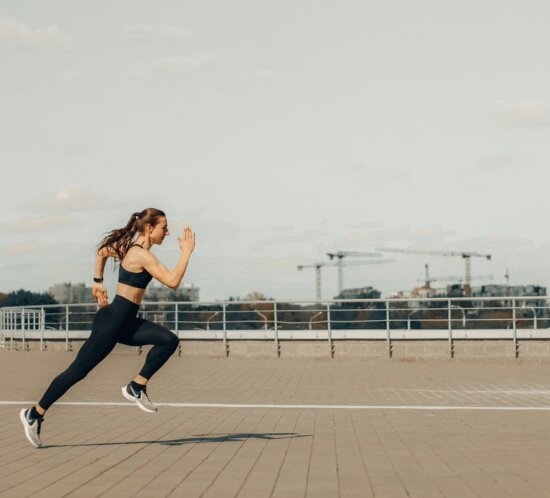 Sportlerin springt athletisch auf Rooftop, Action-Shot ohne erkennbares Wearable