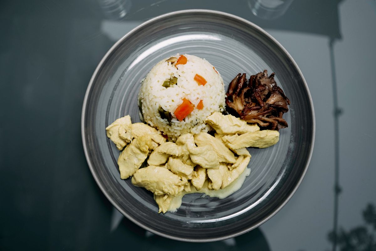 Plato con pollo, arroz y verduras como comida rica en proteínas