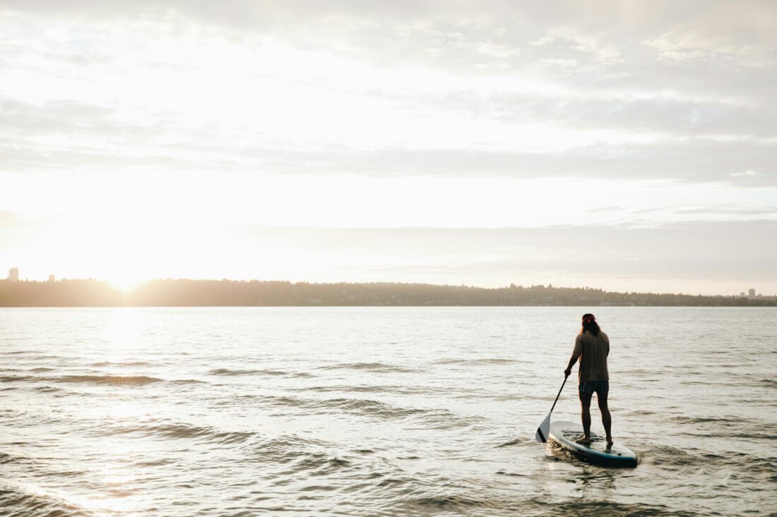 Person beim Stand-Up-Paddling auf ruhigem Wasser