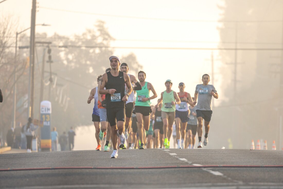 Läuferfeld eines Marathons mit Startnummern auf einer nebligen Morgenstraße
