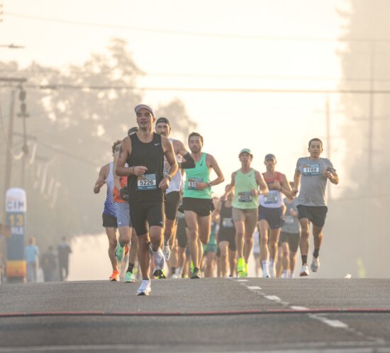 Läuferfeld eines Marathons mit Startnummern auf einer nebligen Morgenstraße